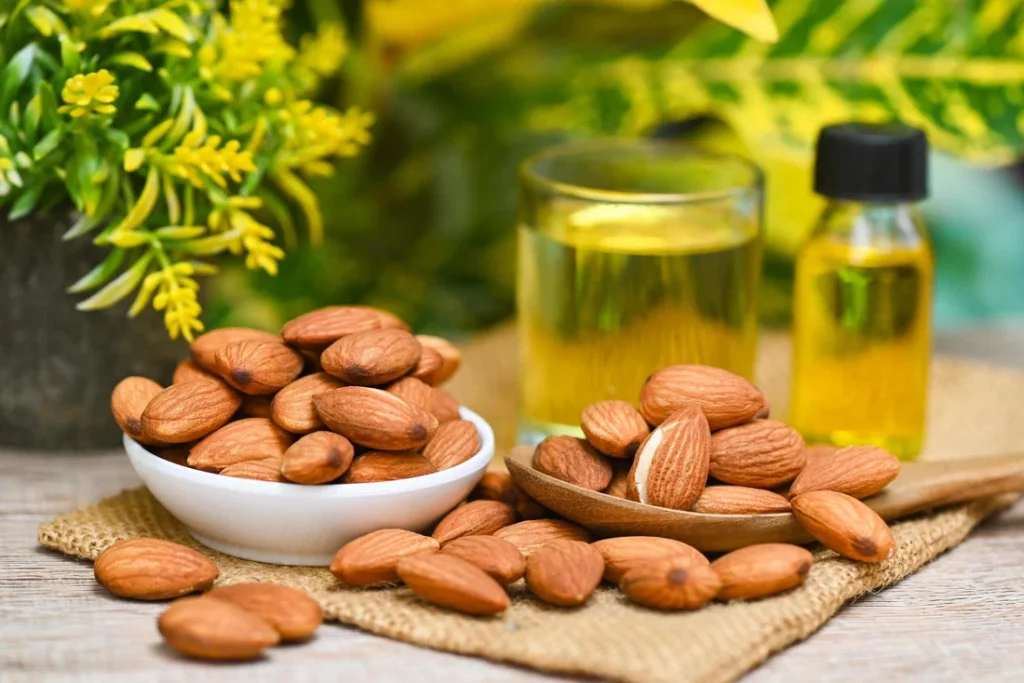 Almond Oil And Almonds Nuts On Bowl Plant Green Nature Background Delicious Sweet Almonds Oil In Glass Bottle Roasted Almond Nut For Healthy Food And Snack Organic Vegetable Oils For